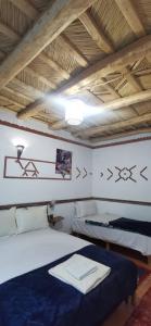 1 dormitorio con 2 camas y techo de madera en Auberge des peupliers Café Restaurant, en Akhendachou nʼAït Ouffi