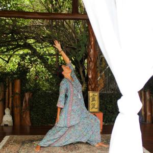een vrouw in een jurk dansend op een kleed bij The Inner Light Yoga Lodge in Sámara