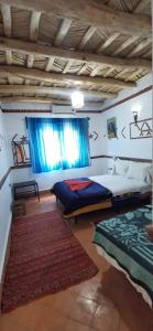 1 Schlafzimmer mit 2 Betten und einem Fenster in der Unterkunft Auberge des peupliers Café Restaurant in Akhendachou nʼAït Ouffi