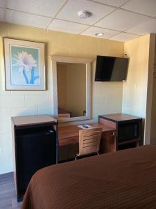 Habitación con cama, escritorio y TV. en Executive Inn & Suites Lackland AFB, en San Antonio