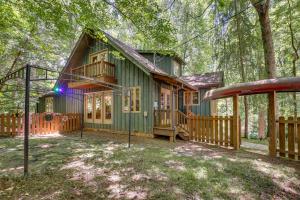 eine grüne Hütte im Wald mit einer Veranda in der Unterkunft Pet-Friendly Conyers Cabin - 23 Miles to Atlanta! in Conyers