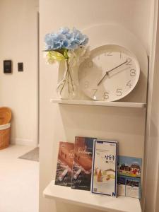 a shelf with a clock and some books at Blue moon stay in Incheon