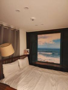 a bedroom with a bed and a window with the ocean at Blue moon stay in Incheon