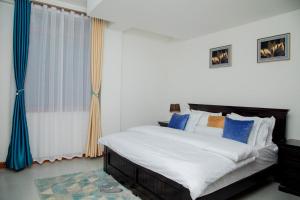Brand New Condo Apartment في كامبالا: غرفة نوم بسرير كبير ومخدات زرقاء وبيضاء