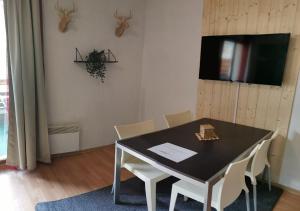 une salle à manger avec une table noire et des chaises blanches dans l'établissement Superbe appartement en résidence avec piscine LES ORRES 1800, aux Orres