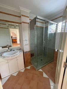uma casa de banho com um chuveiro e um lavatório. em Bungalow familiar con piscina em San Juan de Alicante