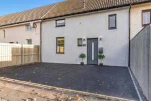 a house with a driveway with two potted plants at Parkside 2 bedroom house near Dunfermline & Edinburgh in Dunfermline