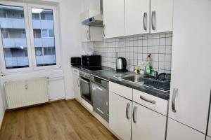 ザルツブルクにあるThe City Appartmentの白いキャビネット、シンク、窓付きのキッチン