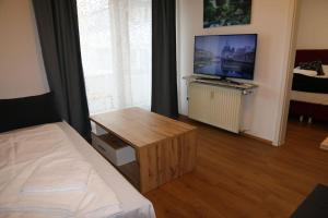 ザルツブルクにあるThe City Appartmentのリビングルーム(ベッド1台、テーブル、テレビ付)