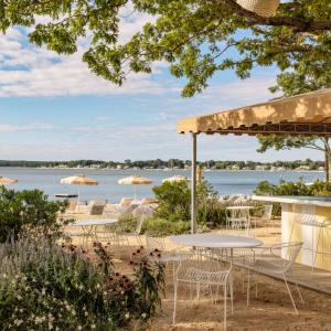 uma vista para uma praia com mesas, cadeiras e guarda-sóis em Silver Sands Motel & Beach Bungalows em Greenport