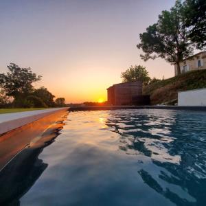 een zwembad met zonsondergang op de achtergrond bij Bessire Chambres & table d'hôtes 