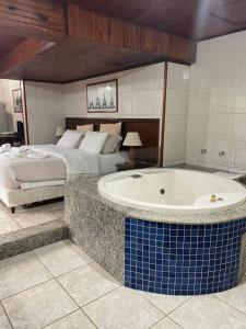 1 dormitorio con 1 cama y bañera en una habitación en Hotel Bougainville, en Penedo
