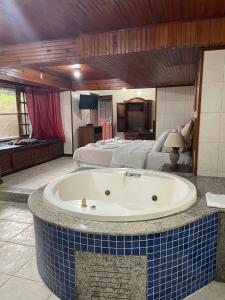 Habitación con 2 camas y baño grande con bañera. en Hotel Bougainville, en Penedo