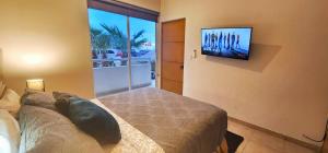 a bedroom with a bed and a tv on the wall at Moderno condo de 1 rec con alberca 5 mins a playa 103b in Cabo San Lucas