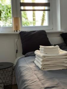 a stack of towels on a bed with a window at Downtown Apartment Murano in Warsaw