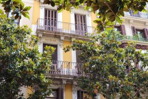 un edificio amarillo con balcones y árboles en Hostal Gràcia, en Barcelona