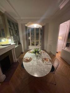 een eetkamer met een tafel en een open haard bij Grand appartement Haussmannien à 12 min de Paris - Proche Stade de France - Jeux Olympiques 2024 in Enghien-les-Bains