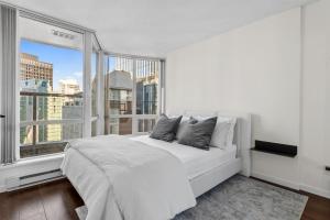 a bedroom with a white bed and a large window at Downtown Luxury 1BR Coal Harbour in Vancouver