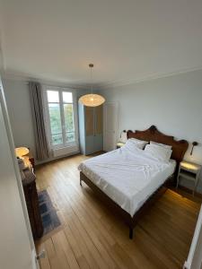 een slaapkamer met een groot bed en een kroonluchter bij Grand appartement Haussmannien à 12 min de Paris - Proche Stade de France - Jeux Olympiques 2024 in Enghien-les-Bains