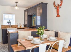 a kitchen with a wooden table with white chairs at White Horses Anglesey in Newborough