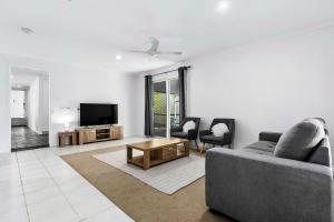 a living room with a couch and a tv at WhiteSands Beachouse in Urangan
