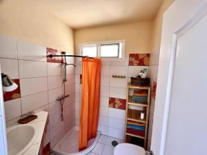 a bathroom with an orange shower curtain and a sink at La Tejita Studio in La Tejita