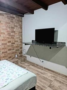 um quarto com uma cama e uma televisão na parede em Suíte e Apartamento Angra dos Reis em Angra dos Reis