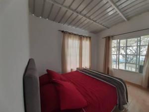 ein rotes Bett in einem Zimmer mit Fenster in der Unterkunft Ecocasa Impresionante panorámica jacuzzi Smart TV in Yumbo