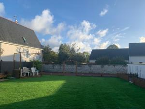 a backyard with a lawn and a stone wall at L'étape de Marcel - Aymé in Avoine