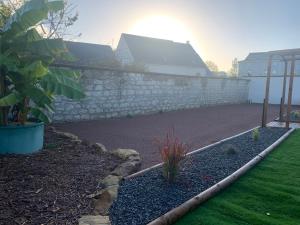 a garden with a stone retaining wall and a yard at L'étape de Marcel - Aymé in Avoine