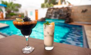 dos cócteles sentados en una mesa junto a una piscina en Fernandina Hotel & Spa, en Puerto Ayora