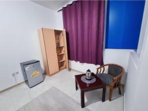 um pequeno quarto com uma mesa e uma cortina roxa em Corniche AD - Extremely Unique Room em Abu Dhabi