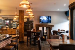 a restaurant with tables and chairs and a tv on the wall at Cozy cottage in Almondbury