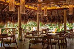 un restaurante con mesas, sillas y sombrillas de paja en Tewimake Hotel, en Santa Marta