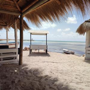a bench on the beach with a straw umbrella at Villa Paco Djerba 2 suites et piscine privée in Taguermess