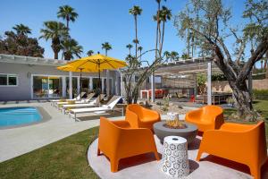 an outdoor patio with orange chairs and a pool at On The Rox- Luxury Refreshing Mid-Century Mod- Pool, Spa, Firepit, Outdoor Kitchen & More in Palm Springs