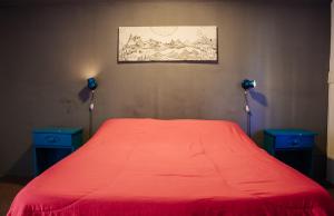 1 dormitorio con 1 cama roja y 2 mesitas de noche azules en Alhue Patagonia Hostel en San Martín de los Andes