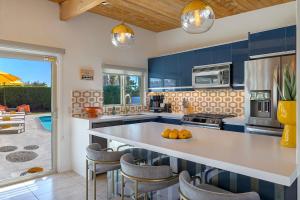 a kitchen with blue cabinets and a counter with chairs at On The Rox- Luxury Refreshing Mid-Century Mod- Pool, Spa, Firepit, Outdoor Kitchen & More in Palm Springs