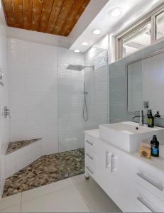 a white bathroom with a sink and a shower at On The Rox- Luxury Refreshing Mid-Century Mod- Pool, Spa, Firepit, Outdoor Kitchen & More in Palm Springs