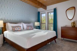 a bedroom with a bed with two pillows and a mirror at On The Rox- Luxury Refreshing Mid-Century Mod- Pool, Spa, Firepit, Outdoor Kitchen & More in Palm Springs +21 photos
