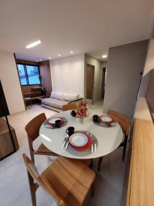 ein Wohnzimmer mit einem weißen Tisch und Stühlen in der Unterkunft Apartamento Luxo 2/4 Beira-Mar Pajuçara - Maceió in Maceió