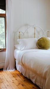uma cama branca com almofadas brancas e uma janela em Auberge des Korrigans em Stoneham