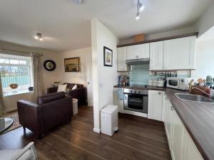 a kitchen with white cabinets and a living room at No 2 Ramageton in Troon