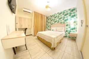 Hotel Natural Green Lounge في تينغو ماريا: غرفة نوم فيها سرير ومكتب