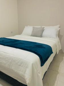 Una gran cama blanca con una manta azul. en Apartamento 202 Entero, en Montería