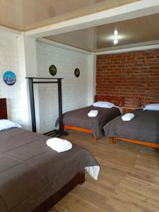Zimmer mit 2 Betten und Ziegelwand in der Unterkunft Rancho Tierra Firma San Miguel de Bolivar in San Miguel
