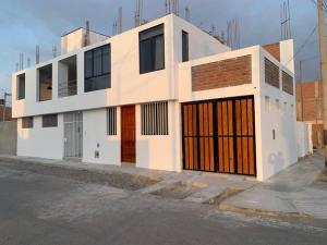 un edificio blanco con puertas naranjas en una calle en Casa San Andrés Arenas con sala de billar, en Pisco