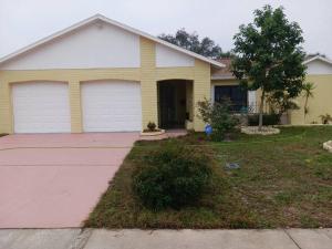 a yellow house with two garage doors and a driveway at Home Away from Home with Heated Pool in New Port Richey