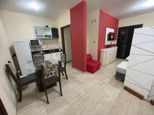 - un salon avec une table et un mur rouge dans l'établissement Flat Paladium, à São Vicente