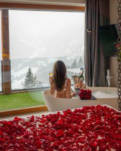 a woman sitting in a bath tub filled with red roses at Hotel Chalet Al Foss in Vermiglio